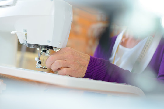Closeup of female hands using sewing machine