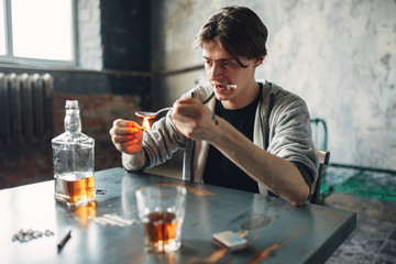 Drug addict with spoon and matches prepares a dose