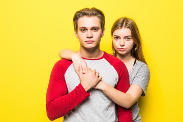 Young happy teen couple hug isolated on yellow background