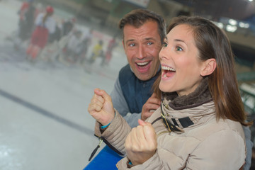 Excited couple cheering on ice hockey team