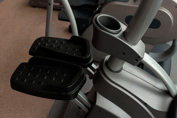 modern new grey and black step machine standing in the gym with pedals close up. concept of sports equipment