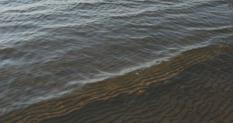 small waves on sandy sea beach on a sunny day