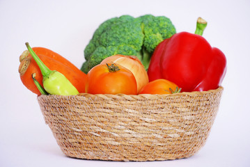 Fresh vegetables carrot and tometos and ginger and green chilli and red bell pepper in the basket on white background.