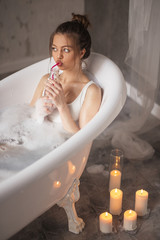 Beautiful woman sits in the tube in hydrotherapy spa and drink cocktail