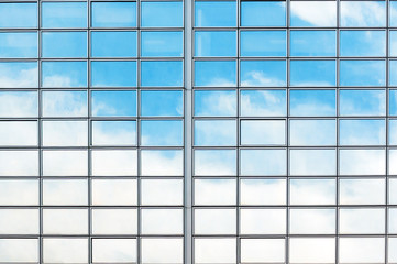 Fragment of modern glass building with the reflection of clouds