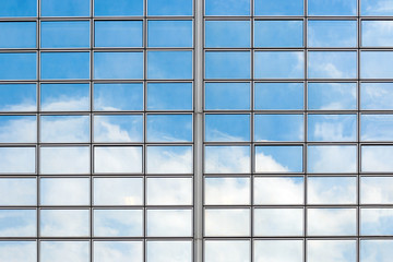Fragment of modern glass building with the reflection of clouds