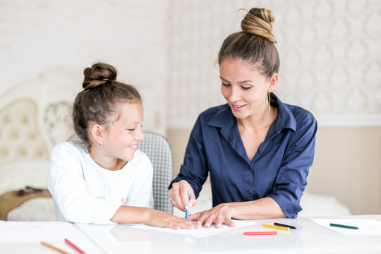 Happy family. Mother and daughter together paint and draw. Adult woman helps the child girl