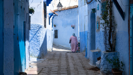 Unidentified woman walking in blue medina of Chefchaouen city in Morocco, North Africa