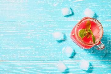 Watermelon smoothie in jar with fresh watermelon slices on blue background top view