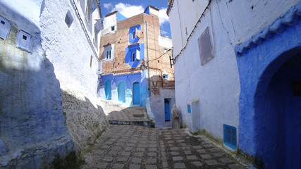 Unidentified man walking in blue medina of Chefchaouen city in Morocco, North Africa
