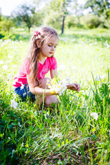 Fototapeta premium little girl in shorts and a T-shirt in a clearing in the summer with flowers