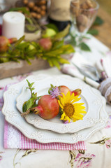 Romantic dinner in the autumn garden, table setting for a nice dinner. Wine, fruit, pomegranate and flowers. Picnic in the open air