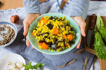 Woman hands holds seasonal vegetable stew with steamed corn, cooked eggplant and carrot. Vegan dinner, vegetarian lunch, healthy food