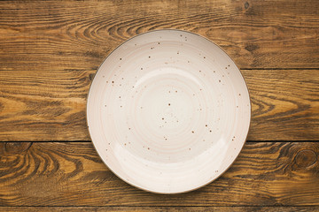 Empty pink ceramic plate on woden table