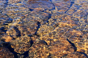 Stones under water for background. Rippled texture water