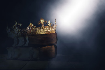 mysteriousand magical image of old crown and book over gothic black background. Medieval period...