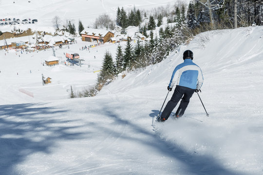 Skier skiing in fresh snow on ski in the mountains on a sunny winter day in Montenegro
