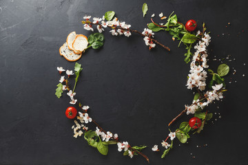 Black table decorated with flowers and ingredients