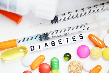 Type 2 diabetes diagnosis from plastic beads with many colourful pills and syringe on white...