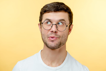 pleasant young man in glasses whistling a song. guy with interesting expression. look up. indifference concept - obrazy, fototapety, plakaty