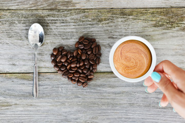 I love coffee quote with natural coffee beans in heart shape on a wooden kitchen table
