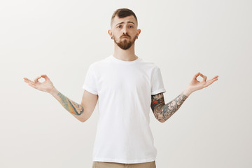 Portrait of calms and serious young guy looking like sensei, standing with spread hands in zed...