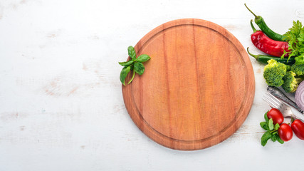 Kitchen board with fresh vegetables. On a wooden table. Top view. Free space for text.