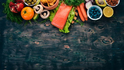 Healthy food. Fish, nuts, fresh vegetables and fruits. On an old wooden table. Top view. Free space for text.