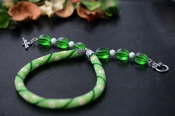 Green summer necklace with chamomile print on a dark background close up