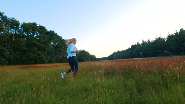 Clip of a happy girl running in a field with red and yellow flowers.