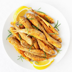 many fried breaded whole fish with rosemary and lemon