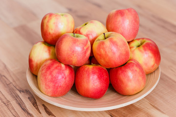 red-yellow ripe apples on a wooden plate