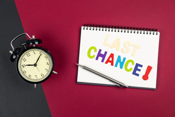 Top view of last chance wording and alarm clock on colorful background