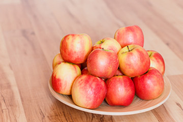 red-yellow ripe apples on a wooden plate