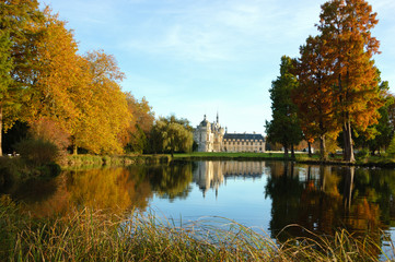 Fototapeta na wymiar View of Chantilly castle reflected in pool surrounded by park trees. Autumn. France.