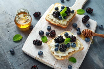Fresh sweet Blackberry, Blueberry bruschetta, toast with cottage cheese, honey in a white board.