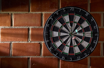Dartboard on a brick wall. 3 darts in the bullseye. 150 bullseye