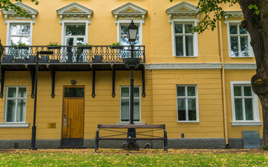 Fototapeta na wymiar Yellow old building, bench and a lamp.