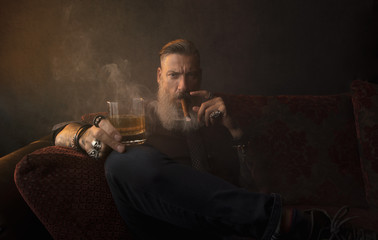Portrait eines attraktiven Geschäftsmannes mit einer Zigarre und einem Glas Whiskey vor dunklem...