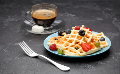 Photo of cup of black coffee with sugar with Viennese waffles with strawberries, raspberries, gooseberries and fork