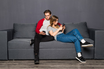 Obraz premium Couple sitting on couch with their phones in their hand. Phone addiction