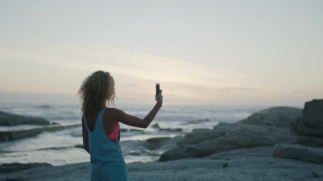 young woman taking photos on beach at sunset beautiful peaceful scenic