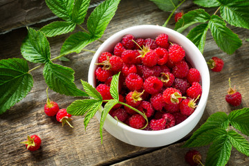 Fresh sweet raspberries in a ceramic bowl on a wooden table. The concept of nutrition for superfoods and health or detoxification.