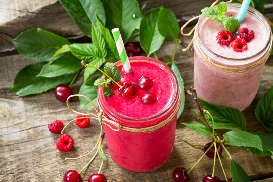 Raspberry and Cherry milkshake or smoothie on a dark wooden table. Healthy juicy vitamin drink diet or vegan food concept.