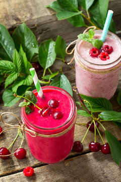 Raspberry and Cherry milkshake or smoothie on a dark wooden table. Healthy juicy vitamin drink diet or vegan food concept.
