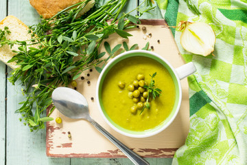 Puree soup with green pea in a bowl on a kitchen wooden table. The concept of healthy eating.  Diet menu. Top view with copy space.