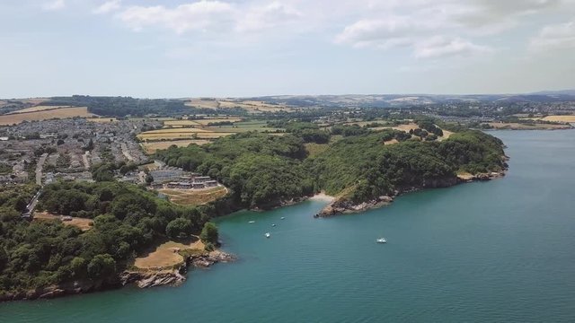 Panorama sky view of beach in Brixham England. Flying over coastal town with harbour and lighthouse.