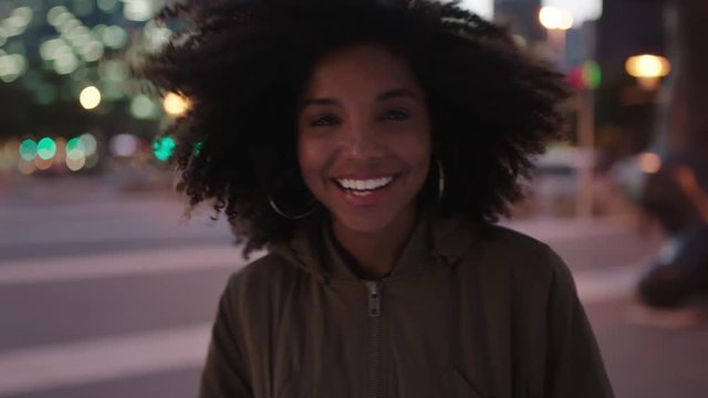 portrait of stylish young african american woman with afro laughing playful enjoying night life in city wind blowing hair urban lifestyle