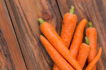 Organic ripe carrots on wood. Top view. Fresh clean carrots on wooden desk surface.