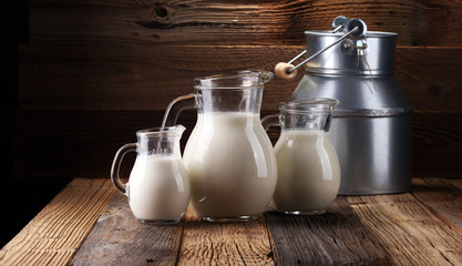 A jug of milk and glass of milk on a wooden table